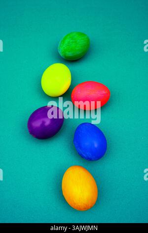 Bright Colored Easter Eggs Arranged Neatly On a Blue Background. Blue, pink, yellow, and green Easter eggs displayed on a blue background for a joyful Stock Photo