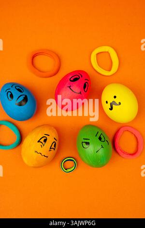 A group of Easter eggs painted with cute emoji faces placed on an orange background Stock Photo