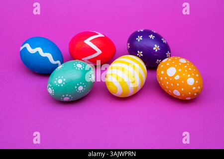 Festive eggs painted with dots and zigzags, lying neatly over a light pink flat surface. Stock Photo
