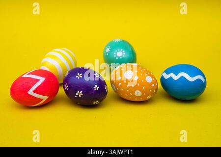 Colorful, decorative Easter eggs laid out on a minimal yellow background, ideal for use in ads, banners, or greeting cards. Stock Photo