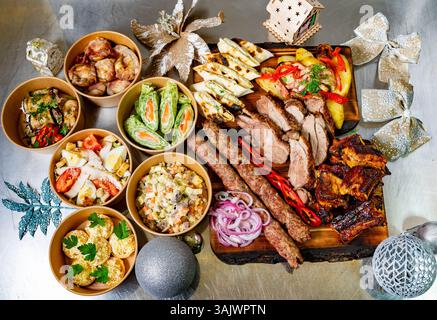 A vibrant display of various carefully arranged dishes, including grilled meats, appetizers, and salads, set on a table decorated for the holiday seas Stock Photo