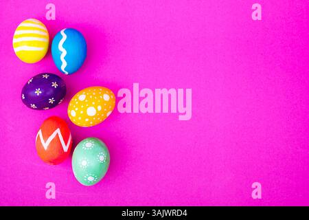 A top view of colorful eggs, offering a spring holiday vibe with a soft light pink setting. Stock Photo