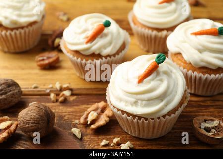 Delicious carrot cupcakes and walnuts on wooden table, closeup Stock Photo