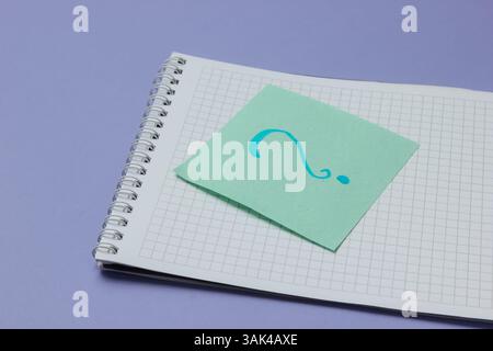 Notepad and memo piece of paper with question mark on a purple background. Stock Photo