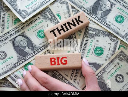 Think big symbol. Wooden blocks with words Think big. Beautiful dollar background. Businessman hand. Business and Think big concept. Copy space. Stock Photo
