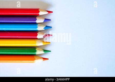 group of colored pencils laud out on a blank white sheet of paper Stock Photo