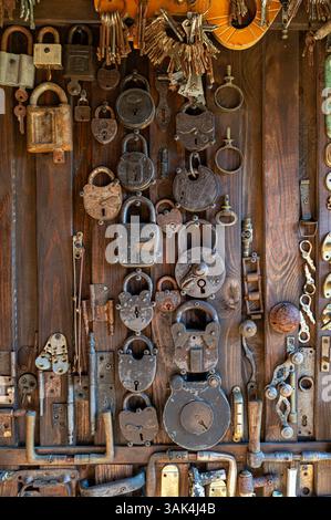 Antique locks and keys arranged on a wooden wall in a rustic workshop setting. Stock Photo