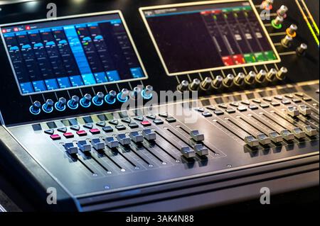 Professional digital audio mixer with illuminated controls and displays in a recording studio Stock Photo