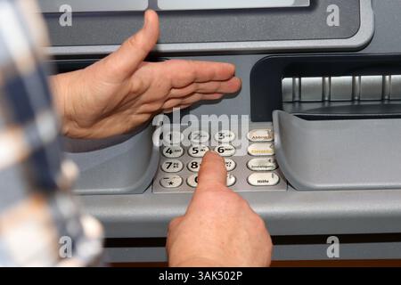 Woman types secret number into cash machine Stock Photo - Alamy