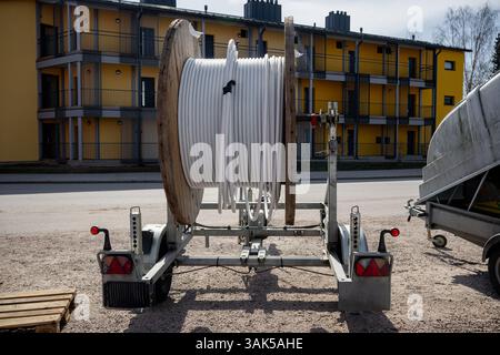 Huge industrial wooden cable spool with coiled white cable on a mobile trailer Stock Photo