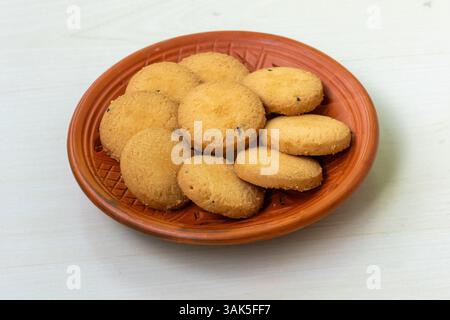 Delicious, salty cookies biscuits on a clay plate, set against a wooden background. Their buttery goodness will leave you craving more. Stock Photo
