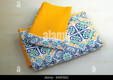 Folded bedsheet and pillow cover with a beautiful floral design on a wooden background. Stock Photo