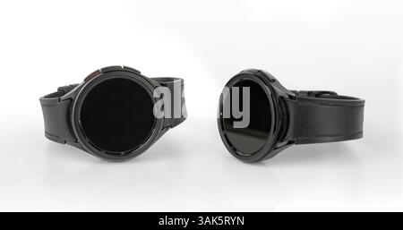 A pair of elegant black smart watches with a leather strap on a white background. There is an outline of the products Stock Photo