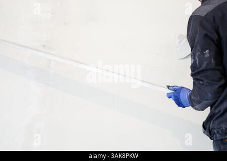 A metal rule for leveling plaster on walls. Applying gypsum plaster in a mechanized way to the wall. High quality photo Stock Photo