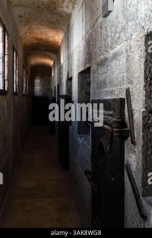 This evocative image showcases the rustic and time-worn prison door found within the Palazzo Ducale in Venice. The aged wood, reinforced with iron ban Stock Photo