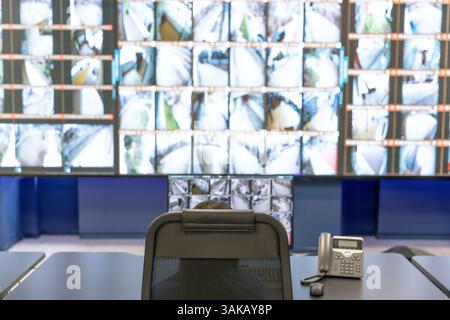 Security officer monitoring multiple surveillance screens in a high-tech control room for safety and surveillance Stock Photo