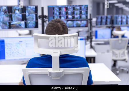 Security officer monitoring multiple surveillance screens in a high-tech control room for safety and surveillance Stock Photo