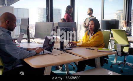 Focused african american businesswoman working on laptop in busy office Stock Photo
