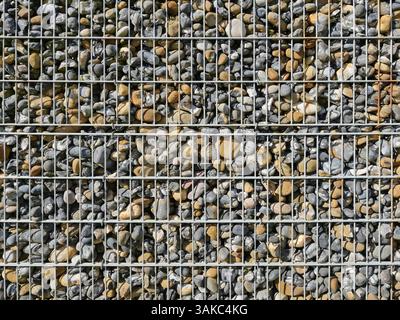 Gabion fence filled with flintstones, stable and durable. Controversial in design but functional as a visual and noise barrier in modern architecture. Stock Photo
