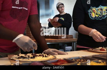 April 12, 2017 - St. Louis, MO, USA - Folding boxes as coworkers make pizzas, Holt Priest looks out for customers at his job at MOD Pizza in Ellisville, Mo., on Wednesday, April 12, 2017. Priest, of Ballwin, works at the pizza restaurant four days a week for two hour shifts where he cleans tables, takes out trash, and folds the pizza boxes. He graduated from Parkway West High School last May. (Credit Image: © Robert Cohen/TNS via ZUMA Wire) Stock Photo