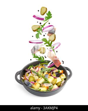 Delicious herring salad isolated on white. Fresh ingredients flying over dish Stock Photo
