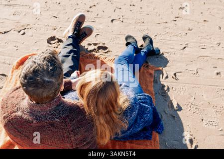 Loving couple walks on beach along sea on sunny autumn day. Weekend and lifestyle concept. Back view. High quality photo Stock Photo