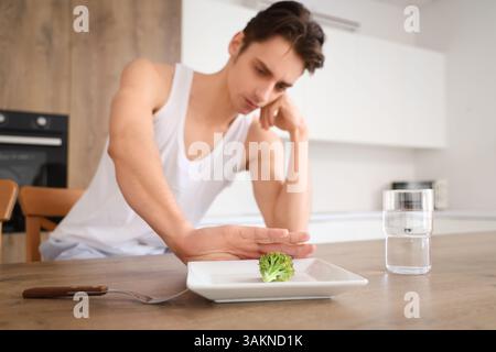 Young man with anorexia refusing from food in kitchen Stock Photo