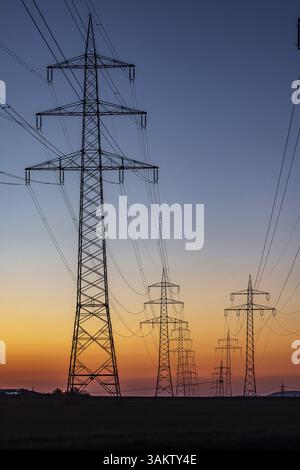 High-voltage pylons, overhead power lines at sunset. Schwieberdingen, Baden-Wuerttemberg, Germany, Europe Stock Photo