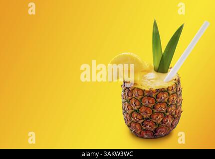 Pina colada cocktail in pineapple with straw, pineapple slices, and two green leaves on the orange background Stock Photo