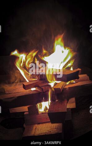 A burning campfire made of logs in the dark that produces warm and bright flames, fire bowl 27798 Hude, Germany, Europe Stock Photo