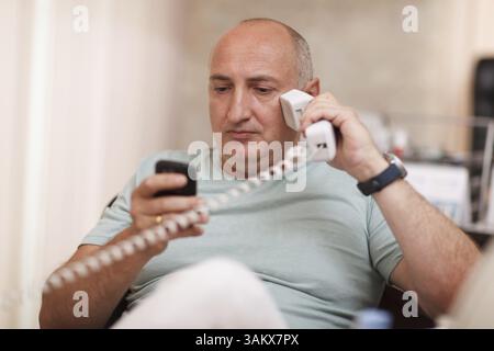 A mature businessman speaking on two phones at once Stock Photo