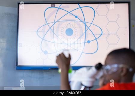 In school, student using microscope in science classroom, focusing on experiment Stock Photo