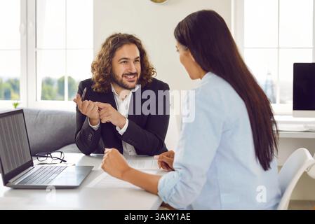 Business people at work in office. Two employers sitting with laptop computer and talking. Stock Photo