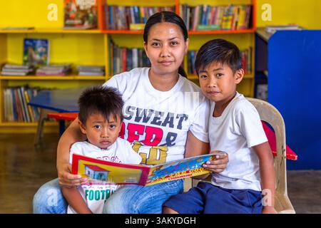 A Filipino mother reads with her two sons at a public elementary school library in Batangas, fostering early literacy and strong family bonds Stock Photo