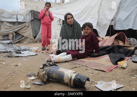 A displaced Palestinian family sits next to their tent, which was ...