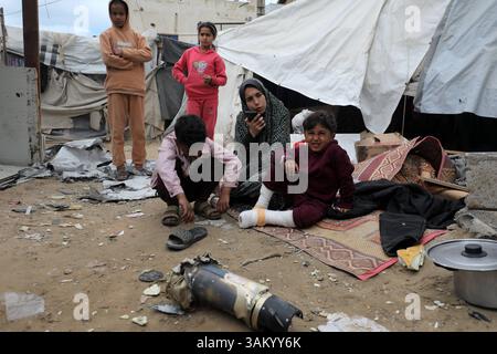 A displaced Palestinian family sits next to their tent, which was ...