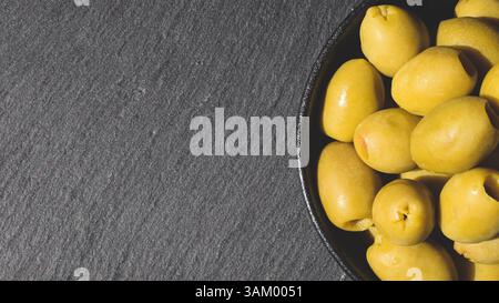 Close-up of green olives on a dark, textured surface. Stock Photo