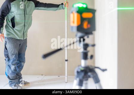 Construction worker using laser level and measuring rod on site Stock Photo