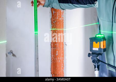 Construction worker using laser level and ruler taking measurements on site Stock Photo