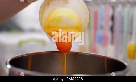 Yellow yolks are added in metal stand mixer bowl. Whipping eggs for baking Stock Photo