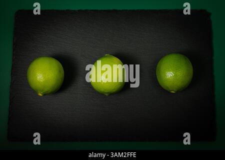 Three Limes on Black Slate – Top View Stock Photo
