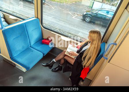 Woman reading a book while traveling with public transportation through the city of Stuttgart in autumn. Stock Photo