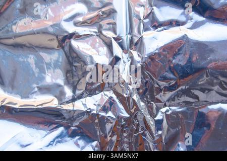 Crumpled reflective shiny gift wrapping material texture background Stock Photo