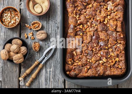 freshly baked Brioche french toast casserole in a baking dish on rustic wooden table with walnuts, horizontal view from above, flat lay, close-up Stock Photo
