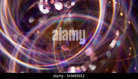 Magical disco. Defocused festive decoration. Multicolor shining attractive particles lens flare motion on blurred bokeh light background. Stock Photo