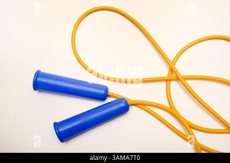 A yellow and blue skipping rope on a white background. Sports equipment. Stock Photo