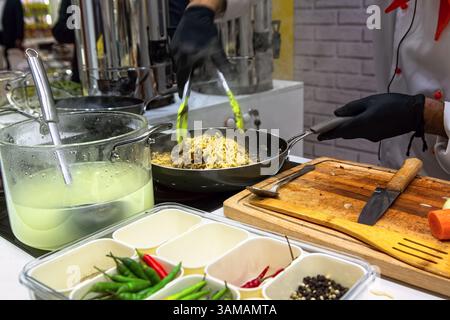 Chef preparing pasta in pan by flipping it in the air in restaurant kitchen. Stock Photo