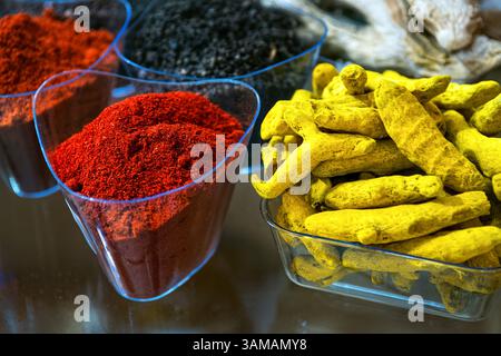 Indian spices. Ground red hot chili pepper and dry yellow turmeric roots in glass bowl. Stock Photo