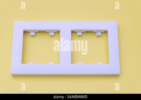 White plastic rectangular frame with two windows for an electrical tray, top view, on a yellow background. Stock Photo