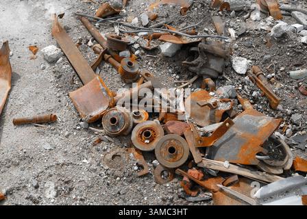A discarded machine part lies in the gravel, rusty and marked by time - a symbol of transience, technology and industrial decay. Stock Photo